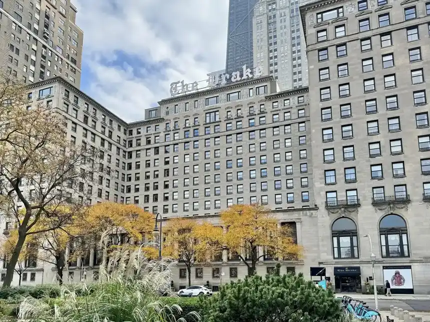 Large historic hotel building behind autumn trees